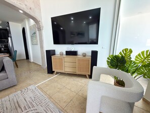 A modern living room with a flat-screen TV, a wooden cabinet, and a grey sofa.