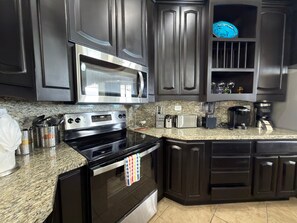 A kitchen with dark cabinetry, a stainless steel microwave, a gas stove, a toaster, and a coffee maker. - Esmeralda Beach Resort 3 Bedrooms C 703 (Puerto Peñasco)
