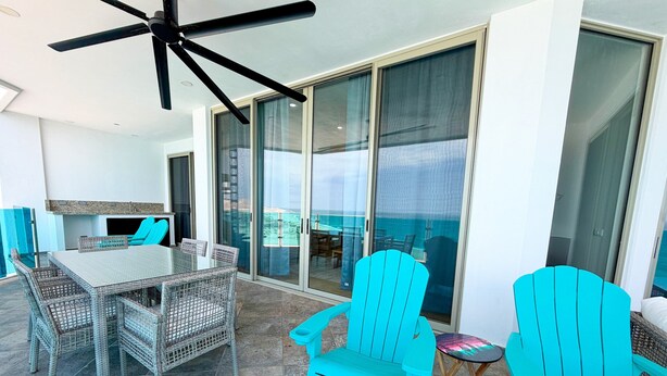 A sunlit patio with a glass door leading to a balcony, a table with chairs, and a ceiling fan. - Esmeralda Beach Resort 3 Bedrooms C 703 (Puerto Peñasco)