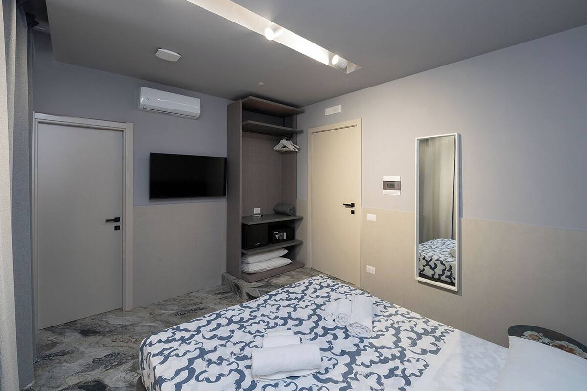 Una habitación de hotel con cama, armario, espejo y televisor.