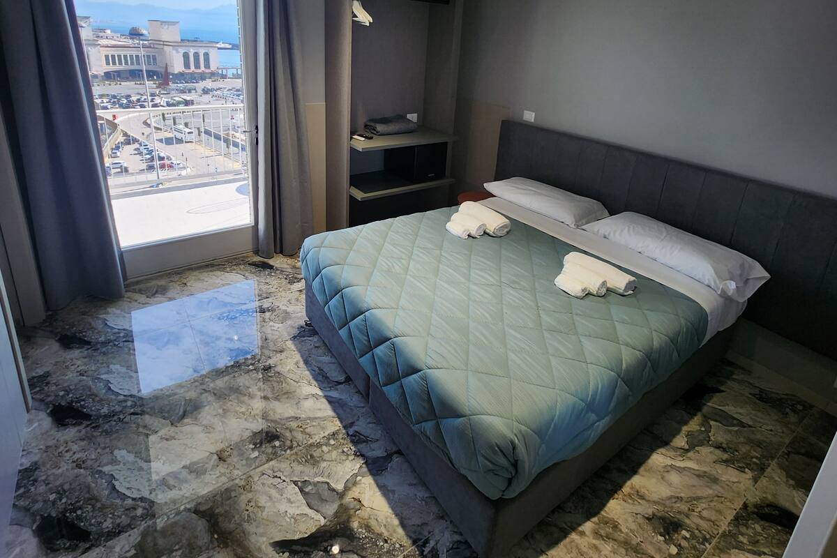 Una habitación de hotel con una cama grande, un armario empotrado, vistas a la ciudad y suelo de mármol.