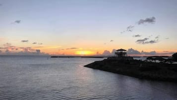 Água calma com uma estrutura à direita, possivelmente um cais ou píer, e céu claro acima.