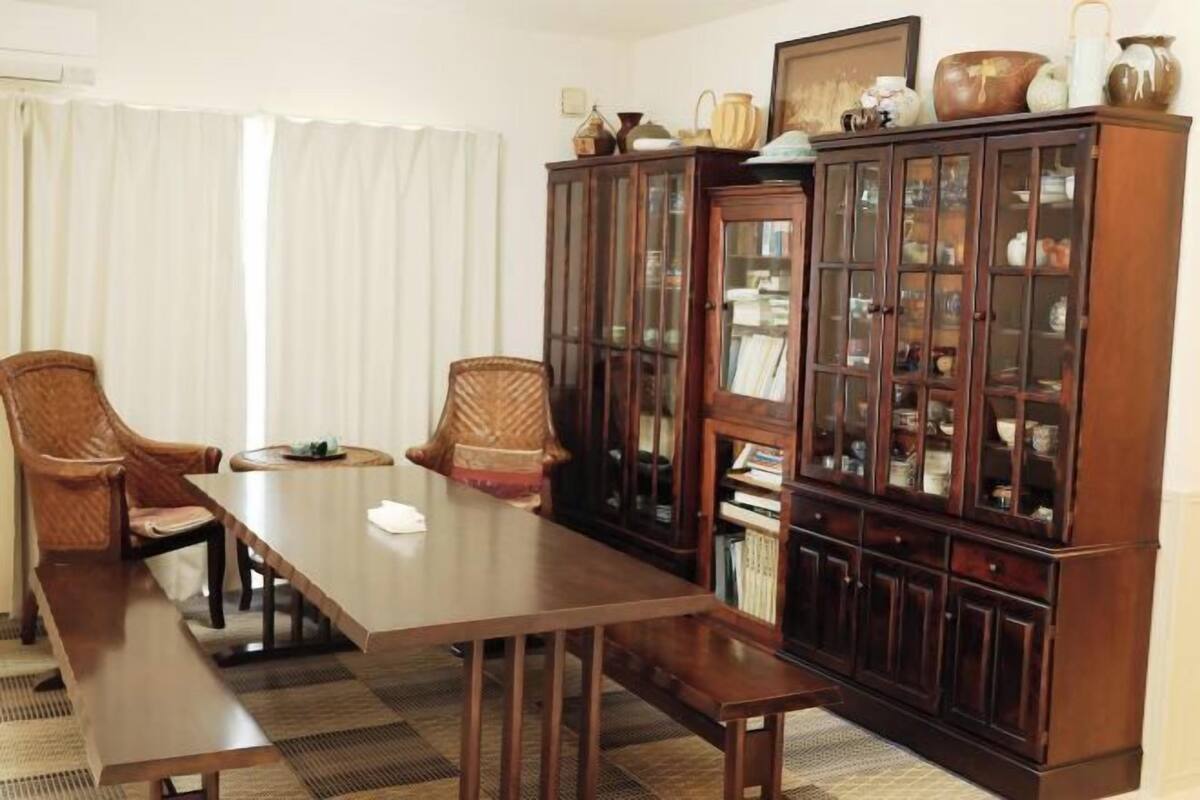 Une salle de conférence avec une longue table, deux chaises et un buffet en bois doté de portes en verre.