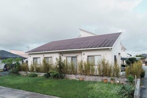 A single-story residential building with a flat roof, surrounded by a well-maintained lawn and a variety of plants. - 15 Minutes to Airport~1 Minute Walk to Beach YeHeJu (Itoman)