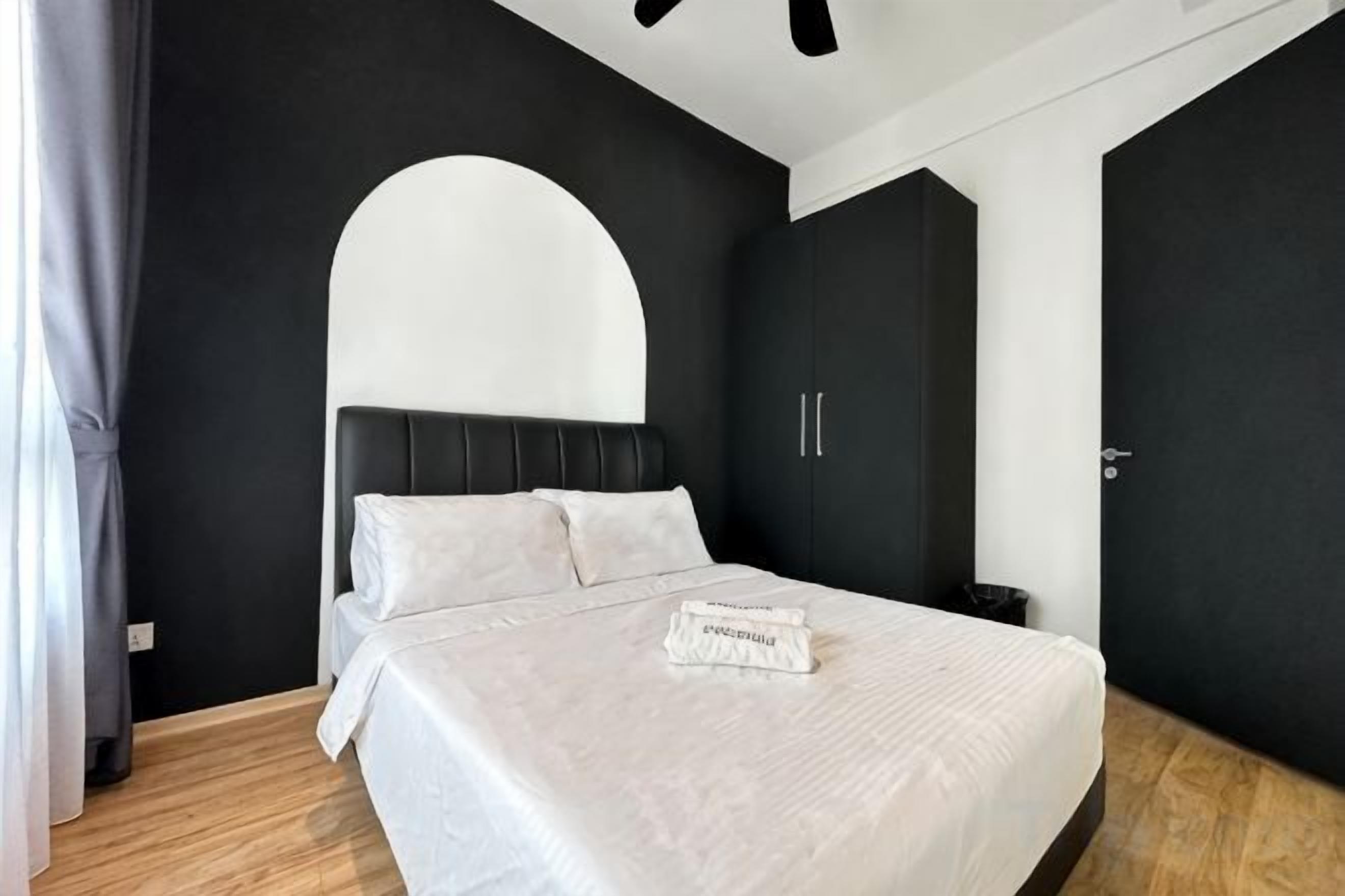 A modern bedroom with a bed, a curved wall, and a wardrobe.