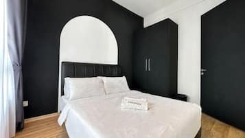 A modern bedroom with a bed, a curved wall, and a wardrobe.