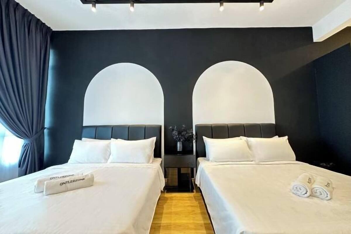 A hotel room with two beds, dark walls, and a modern design.