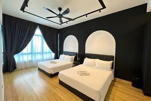 Una habitación de hotel moderna con dos camas, un ventilador de techo y ventanas amplias con cortinas.