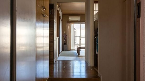 A hallway with wooden flooring, a bench, and a door on the right. - Higashi Mukojima 4 Room (Tokyo)