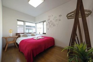 A bedroom with a bed, a bedside table, a window, and a wall decoration. - Higashi Mukojima 4 Room (Tokyo)