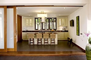 A kitchen with a central island, bar stools, and a large window. - Villa Haineu (Koh Samui)