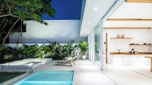 A modern outdoor kitchen with a pool, surrounded by lush greenery and a clear sky. - ULU 5 ·2br Villa (Bali)