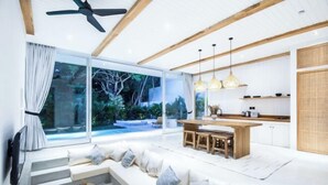 A modern living room with a sofa, a wooden coffee table, and a dining area with a table and chairs. - ULU 5 ·2br Villa (Bali)