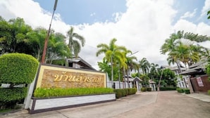 A residential area with a signboard, palm trees, and houses. - Royal Boat Pool Villa - Pattaya (Pattaya)