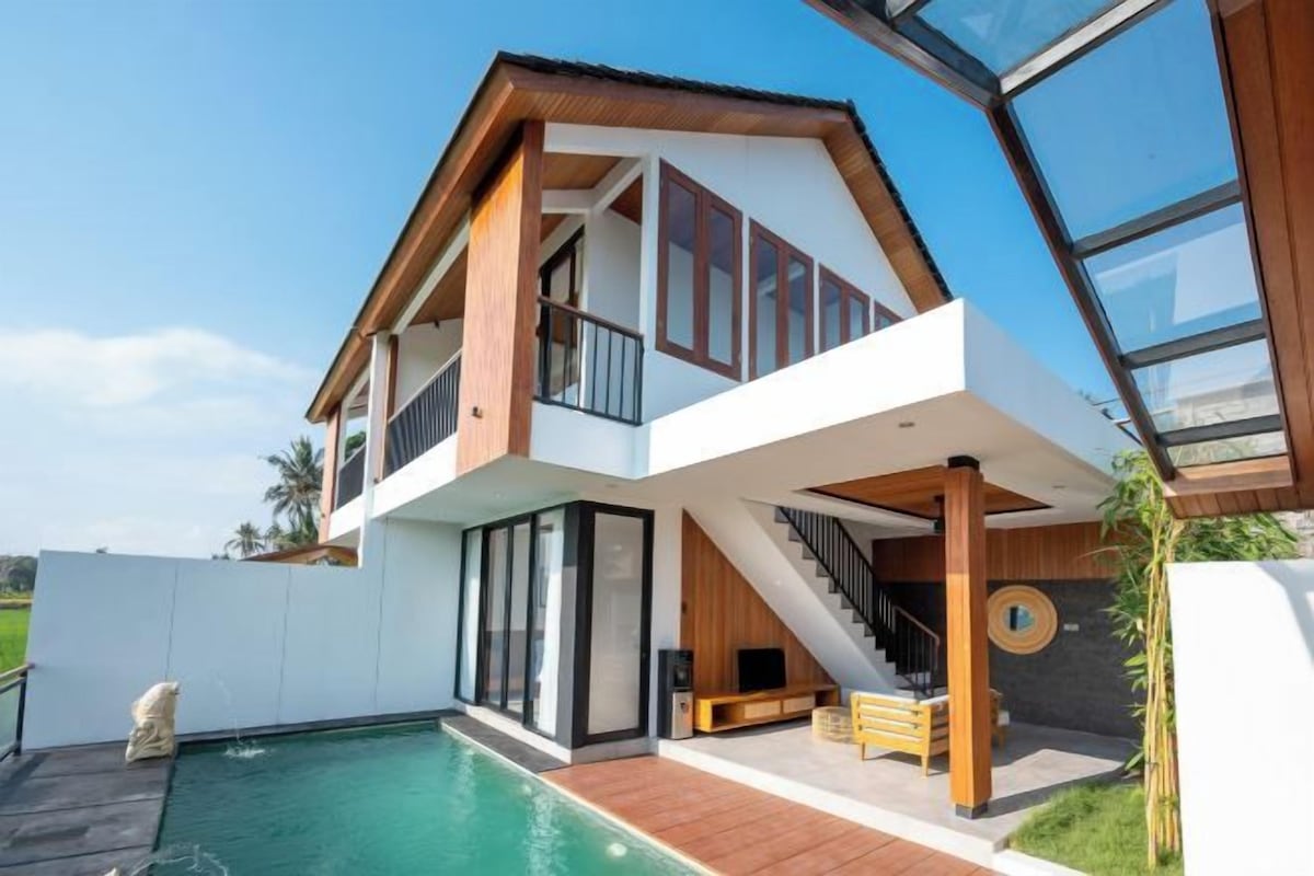 A modern two-story house with a swimming pool, large windows, and a staircase leading to the upper floor.