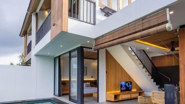 A modern multi-story house with a swimming pool, a staircase, and a living area with a TV. - Kairos Villa Ubud (Bali)