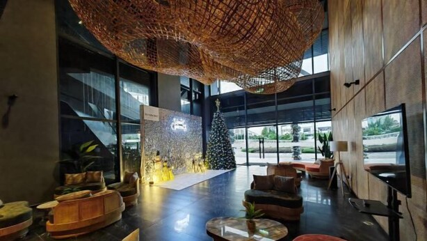Un vestíbulo moderno con un gran árbol de Navidad, zonas de estar cómodas y un amplio ventanal con vistas al exterior.