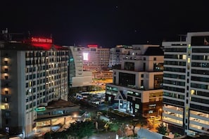 A cityscape at night with illuminated buildings, including a hotel with a red sign. - Sutera Bay Luxe Haven Suite Infini Stay (Kota Kinabalu)