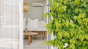 Una habitación acogedora con un sofá blanco, una pequeña mesa de madera y una pared cubierta de plantas verdes.