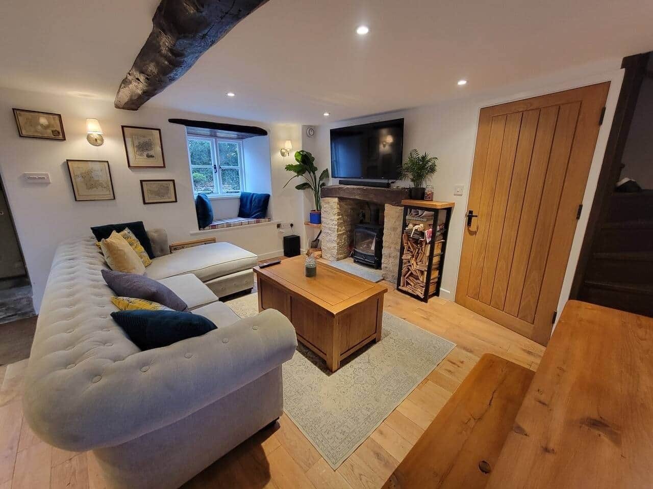 A modern living room with a sofa, coffee table, fireplace, and television.