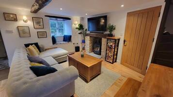 A modern living room with a sofa, coffee table, fireplace, and television.