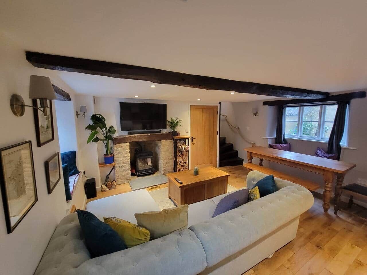 Una sala de estar acogedora con sofá, chimenea, televisor y una escalera que sube.