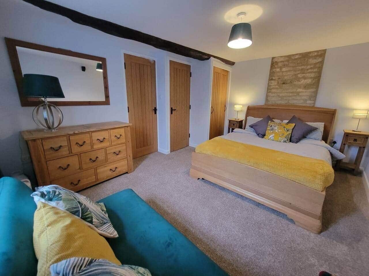 Een slaapkamer met een bed, een dressoir, een spiegel en een plafondlamp.