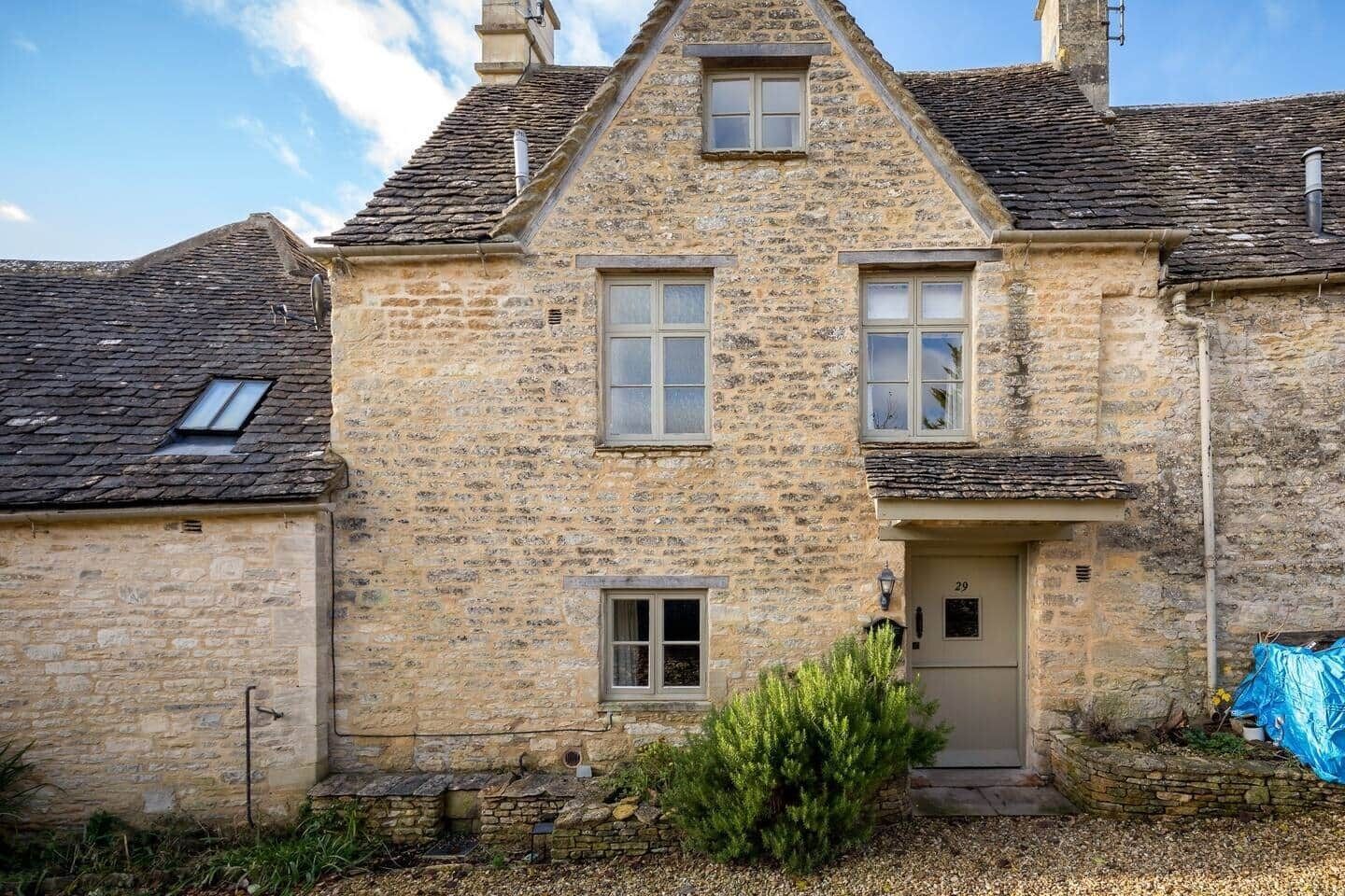 A stone building with a gabled roof, a front door, and two windows.