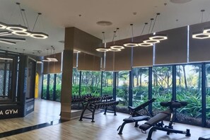 Un gimnasio con equipo de ejercicio, ventanas amplias y suelo de madera.
