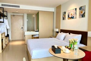 A hotel room with a bed, bedside table, mirror, artwork on the wall, and a red chair. - Resort CAM RANH DELUXE SEAVIEW (Cam Ranh)