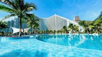 A hotel with a large swimming pool, palm trees, and a modern building.