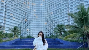 A modern hotel with a curved facade, palm trees, and a well-maintained lawn. - Resort CAM RANH DELUXE SEAVIEW (Cam Ranh)