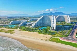 A large resort with multiple high-rise buildings, a beach, and a mountainous backdrop. - Resort CAM RANH DELUXE SEAVIEW (Cam Ranh)