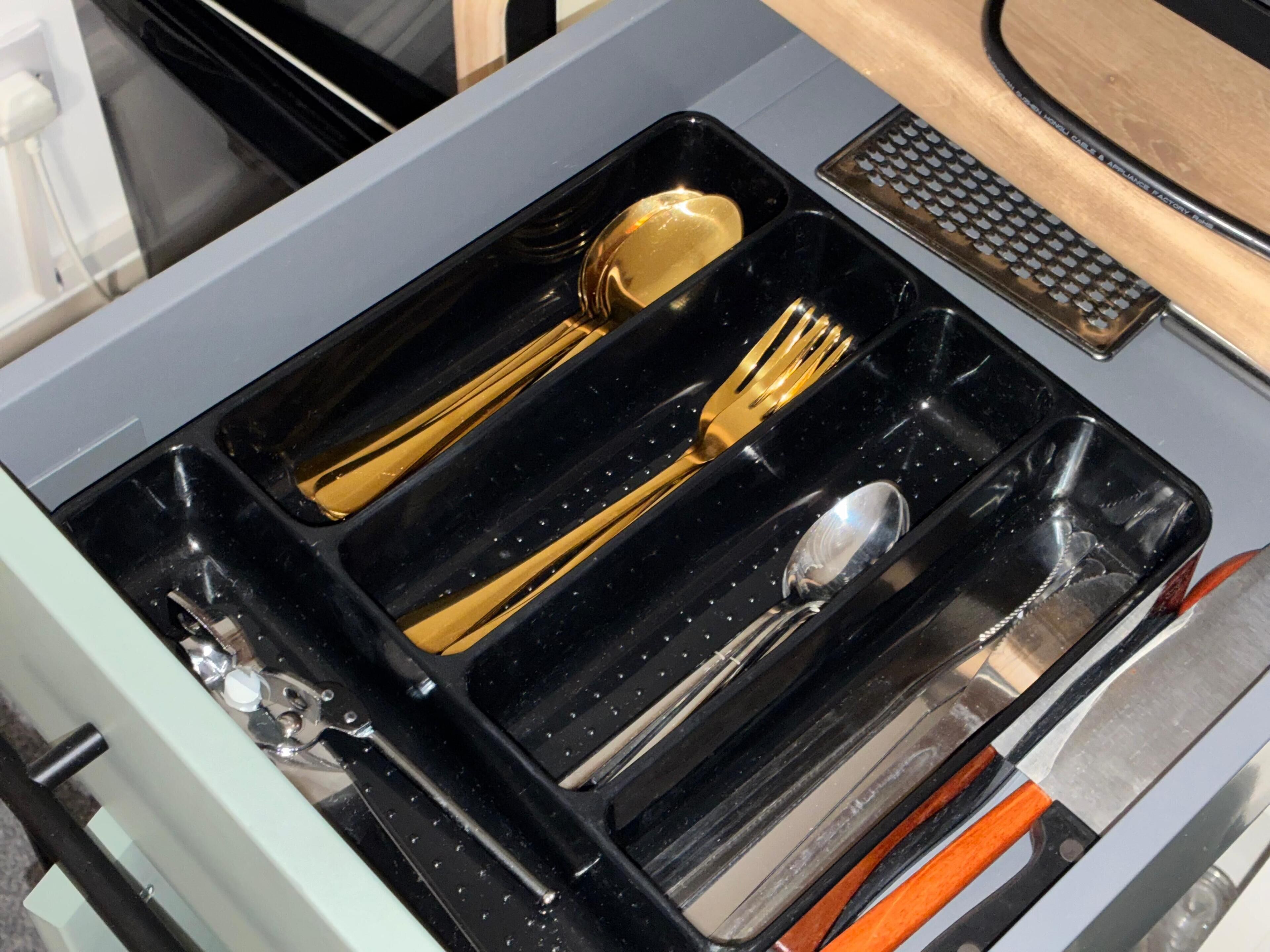A drawer with compartments containing a spoon, fork, and knife.
