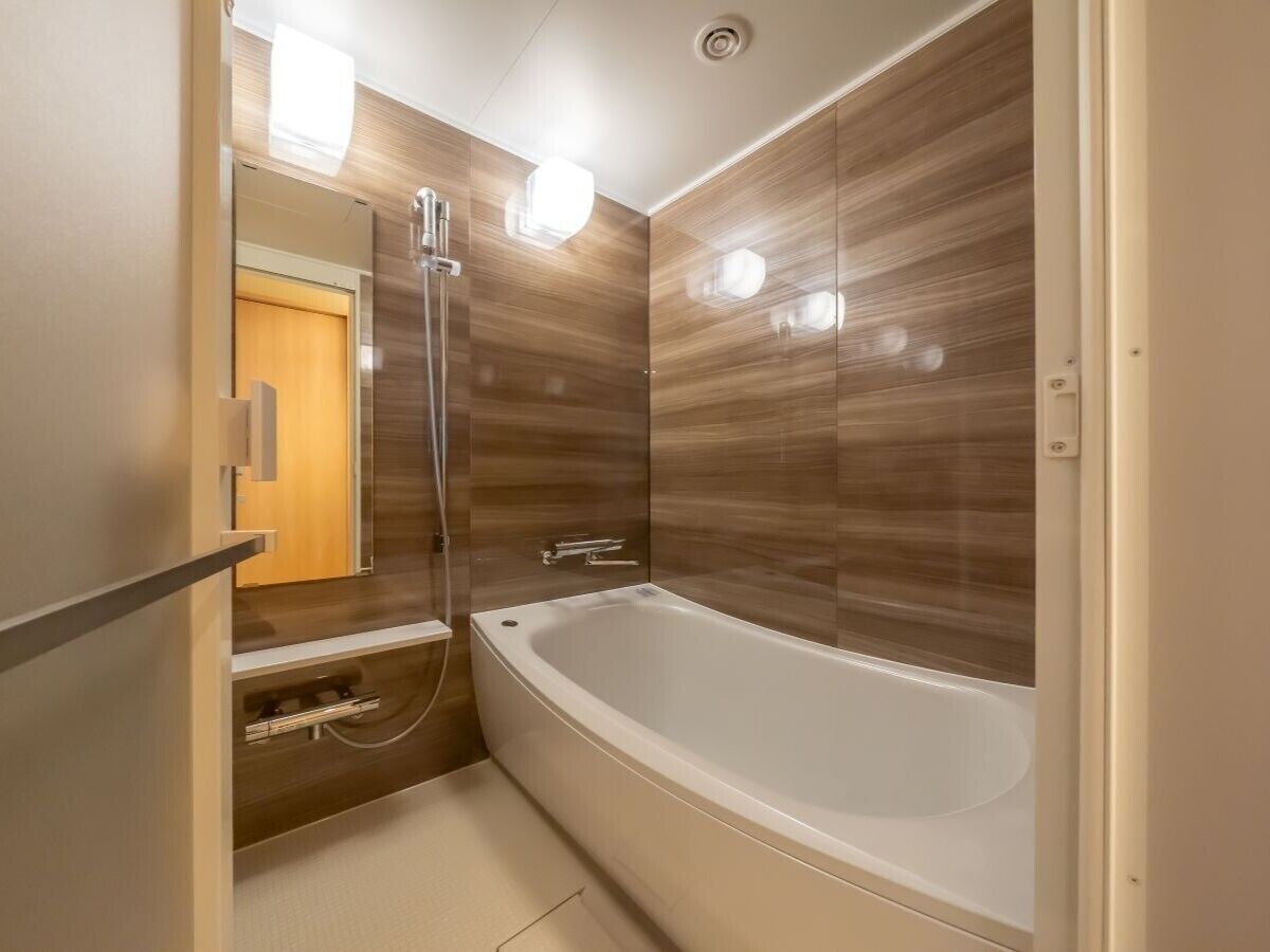 A bathroom with a bathtub, a shower, and a vanity with a mirror.