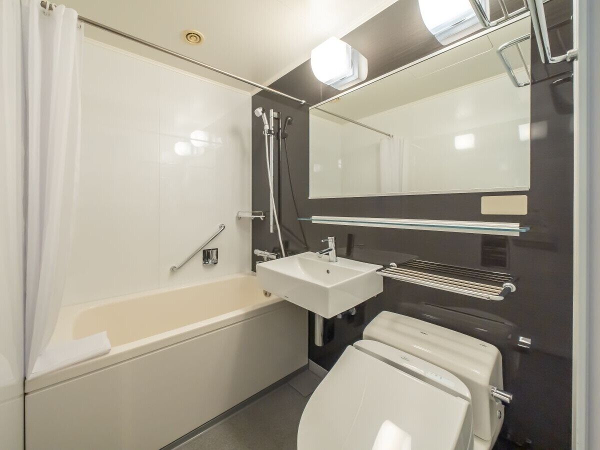 Un baño moderno con bañera, lavabo, inodoro y espejo.