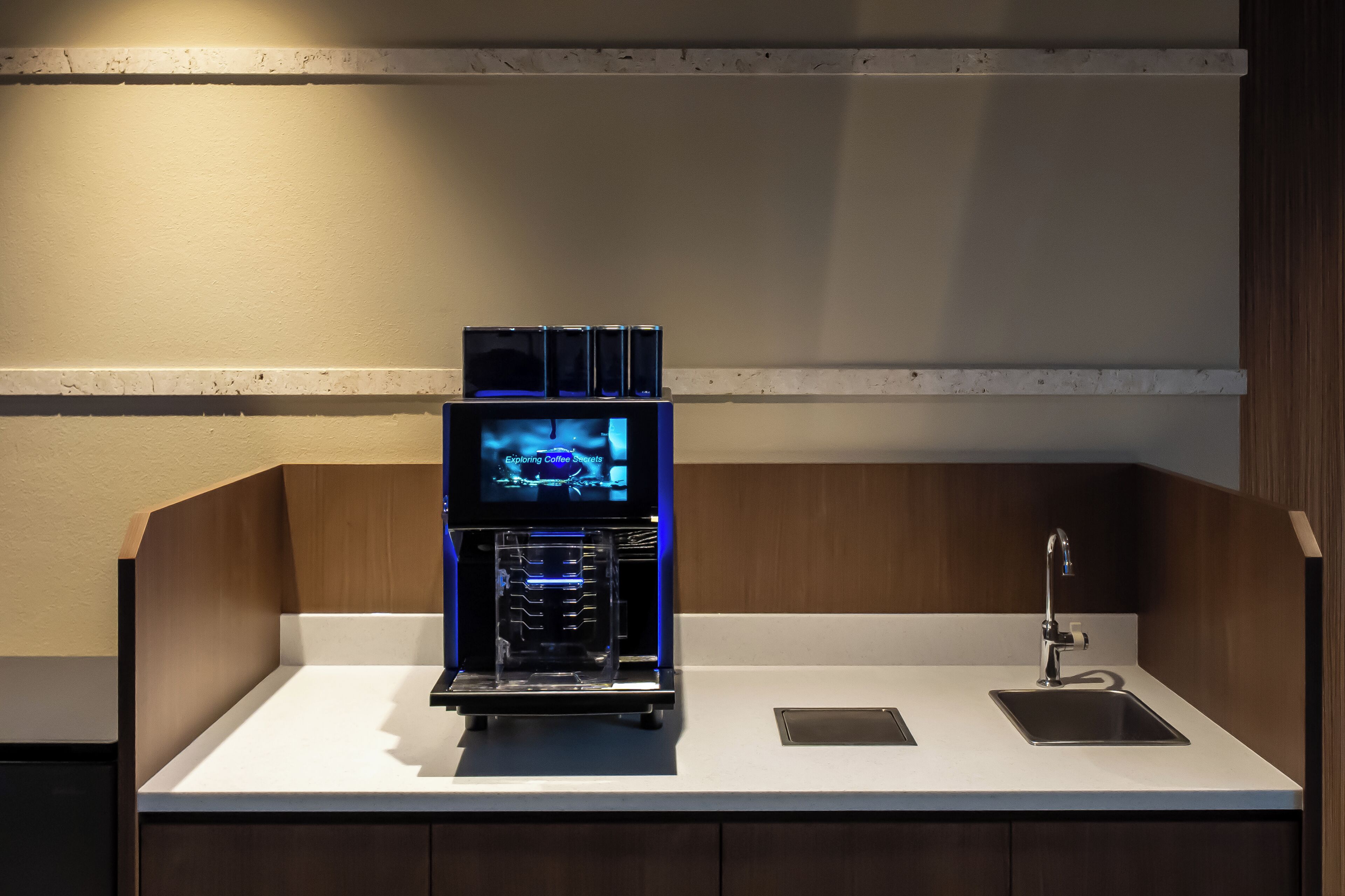Eine Kaffeemaschine mit digitalem Display, ein Waschbecken und eine Arbeitsplatte.