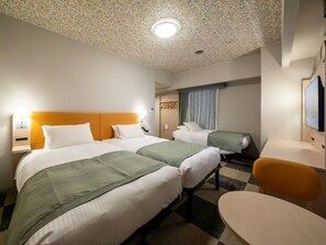 Ett hotellrum med två sängar, ett skrivbord, en stol och ett tak med ett bladmotiv.