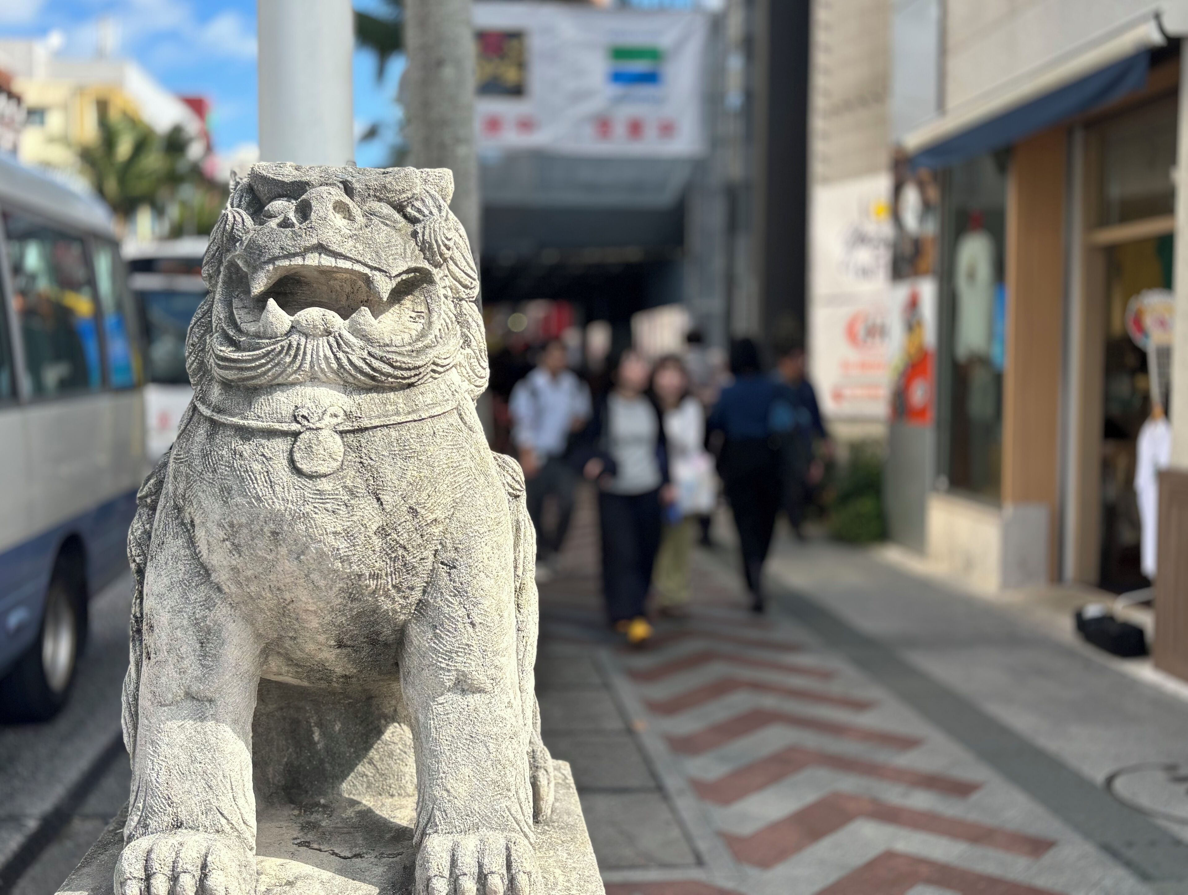 A stone lion statue on a city sidewalk.
