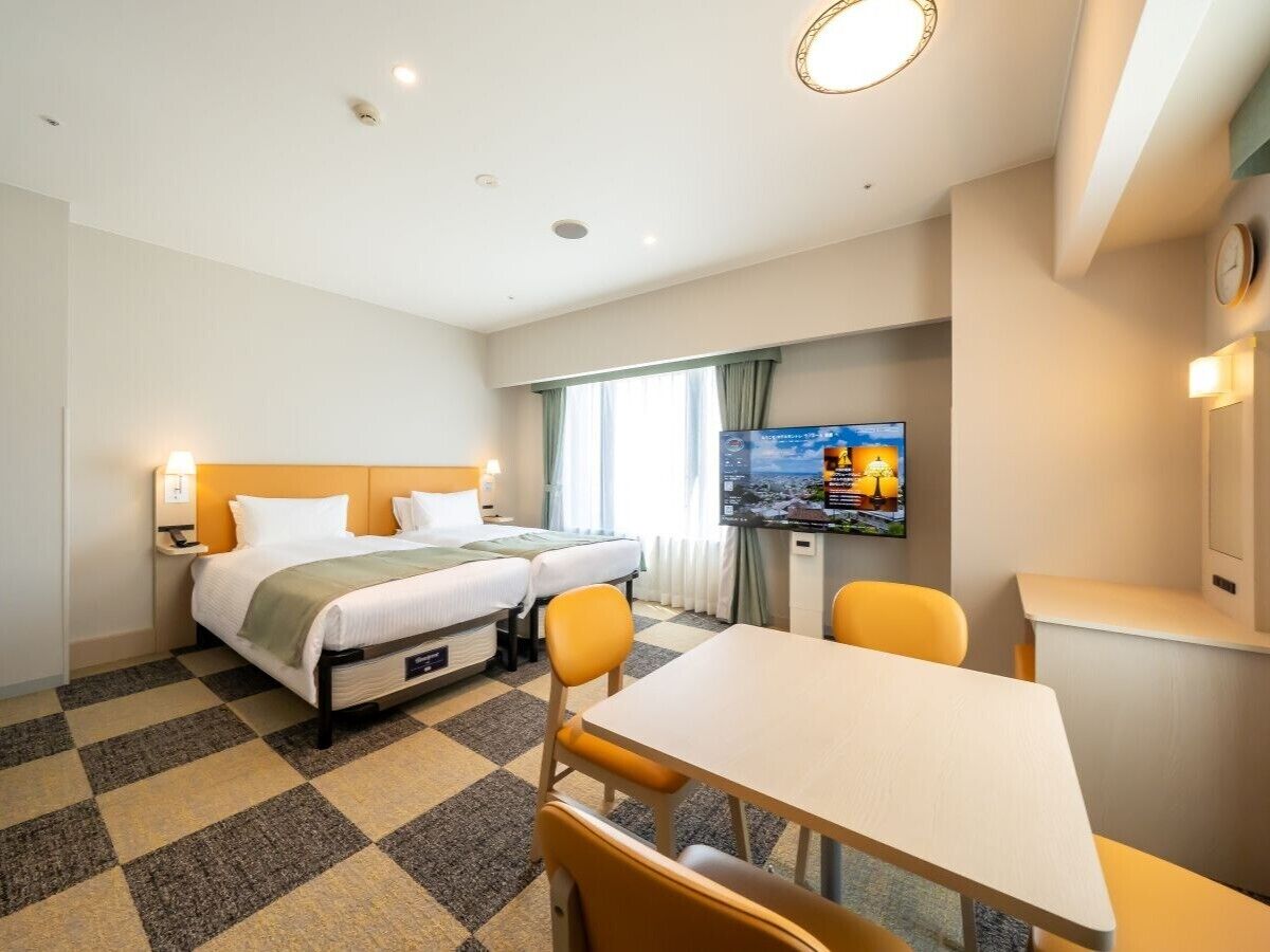 Hotelkamer met twee bedden, een televisie, een eettafel en een receptiebalie.