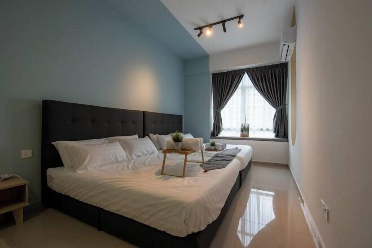 A modern bedroom with a large bed, a bedside table, a window with curtains, and a ceiling light fixture.