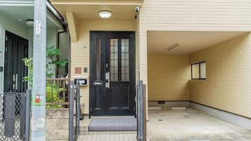 A building entrance with a black door, a small porch area, and a tiled ground.