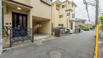 A residential street with a beige building, a black gate, and a person walking.