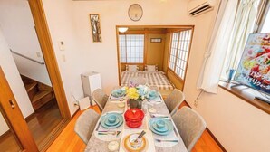 Una habitación tradicional japonesa con suelo de tatami, una mesa baja preparada para comer y un puertas correderas que dan a otra habitación.