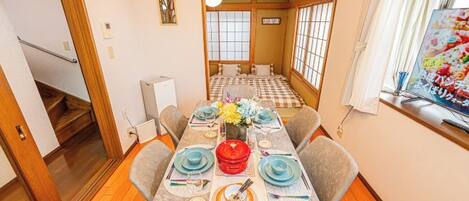 A traditional Japanese-style room with tatami flooring, a low table set for dining, and a sliding door leading to another room.