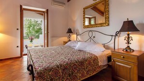 A bedroom with a bed, bedside tables, a mirror, and a view of an outdoor balcony. - Villa Ana, Spacious 5 Bedroom Retreat with Access to 2 Shared Pools (Koromačno)