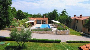 A swimming pool with a stone deck, surrounded by a stone wall and a grassy area. - Villa Ana, Spacious 5 Bedroom Retreat with Access to 2 Shared Pools (Koromačno)