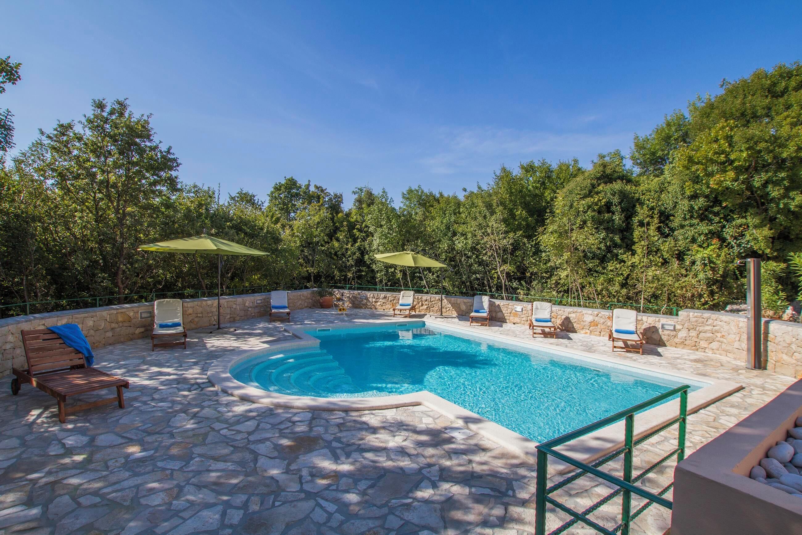 A swimming pool with a stone patio and lounge chairs.