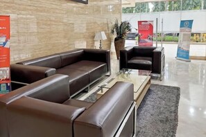 A modern lobby with leather sofas, a glass coffee table, and a potted plant. - Strategic MTH Square Apt 1BR w/ Pool & Gym (East Jakarta)
