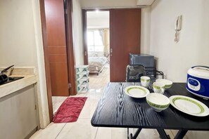 A kitchen with a dining table set for four, a red rug, and a view into a bedroom. - Strategic MTH Square Apt 1BR w/ Pool & Gym (East Jakarta)
